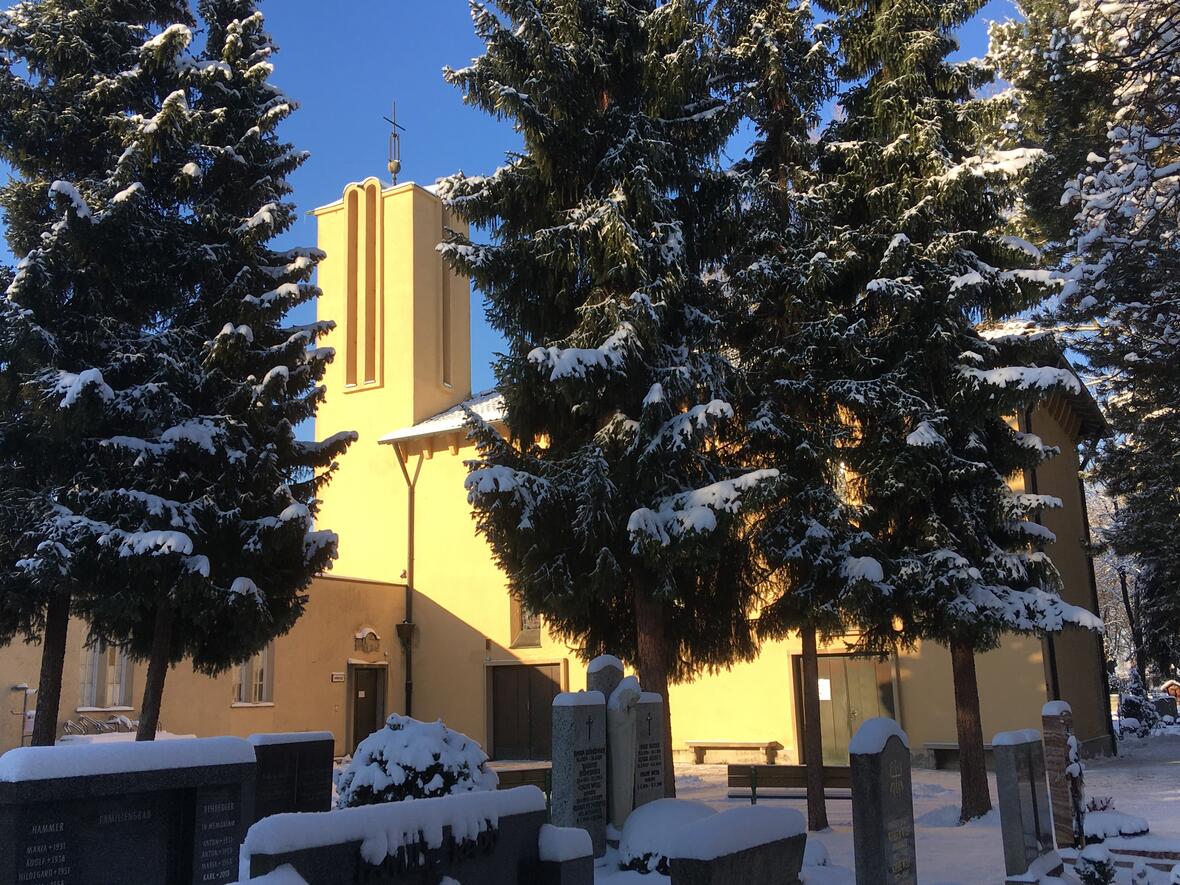 Winterbild der von der Sonne angestrahlten Außenfassade der Aussegnungshalle auf dem Hermanfriedhof nach Schneefall