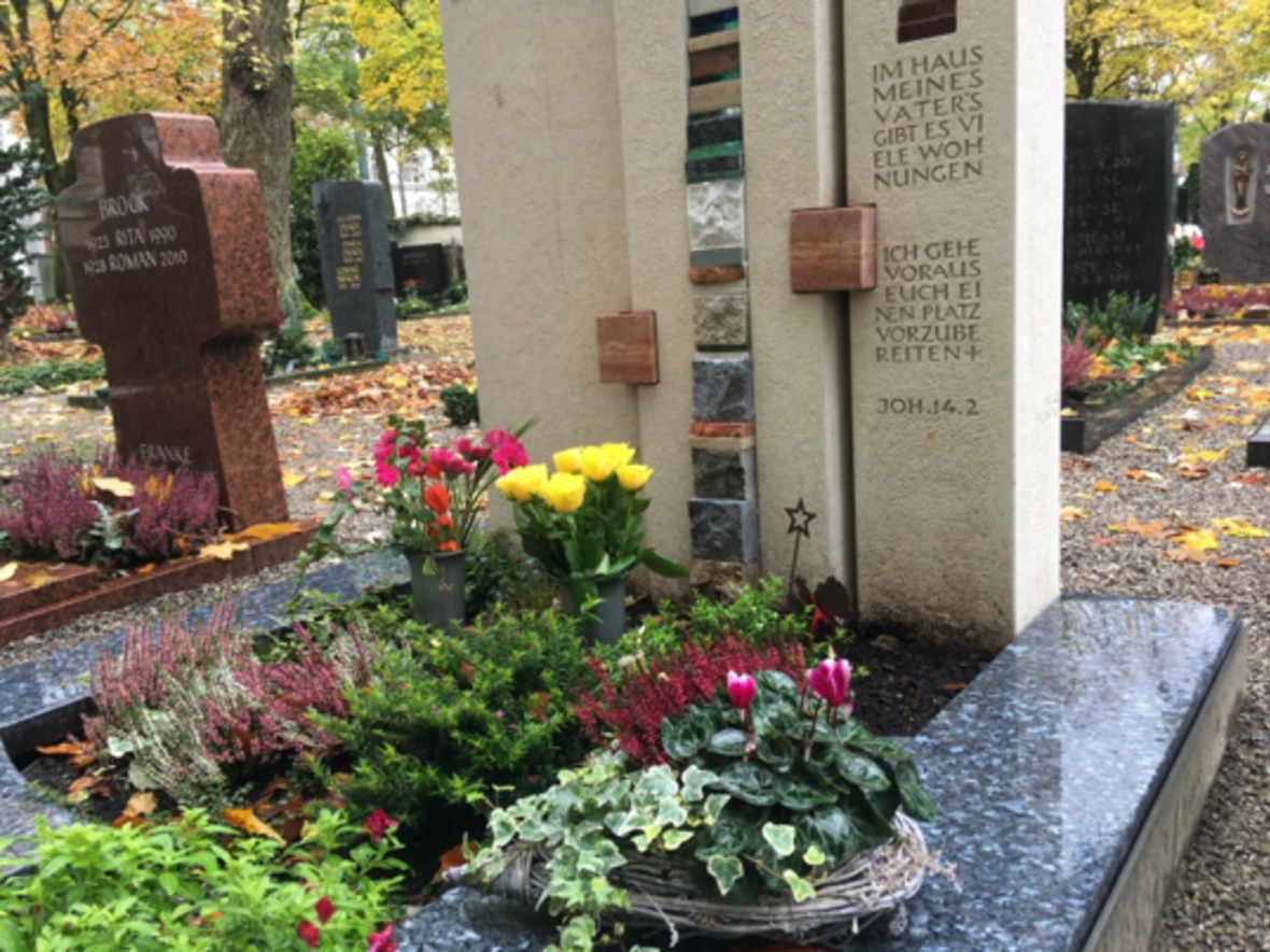 ein mit Blumen bepflanztes klassisches Doppelgrab mit weißem Grabstein